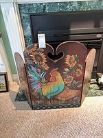 Front view of entire three-panel painted fireplace screen in front of fireplace