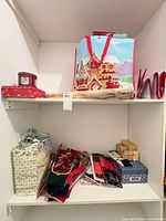 Shelf showing assorted gift bags, red star gift box, Christmas gift bag, red cylindrical box, ribbon