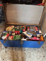 Open blue trunk showing assorted boxed lights and accessories