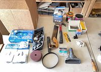 Overall view of lot on table showing hammer, saw, glove box, sanding disc, vacuum attachments, hardware trays, dust mask