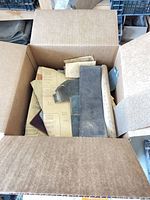 Box containing various 3M sheets, off-cuts and belt pieces