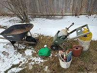 Overall lot showing wheelbarrow, spreader, sprayer, watering cans, buckets and snow background