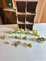 Full lot showing wood cubby shelf and all frog figurines arranged in front