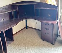 Full view of L-shaped desk showing curved surface, shelves, pedestal, center support