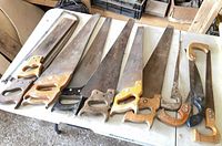 All nine wood-handled saws laid out on table