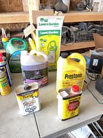 Table with Prestone coolant, purple coolant, Minwax Tung Oil, Sunnyside refinisher, Chapin sprayer box, Weed-B-Gon jug