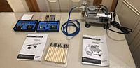 Full kit on table showing compressor, hose, airbrushes in cases, paint jars, carving tools, manuals