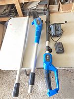 Full view of disassembled Mastercraft pole chainsaw with extension sections, battery and charger on table