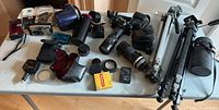 Entire lot laid out on table showing cameras, lenses, film, flash, tripod and accessories