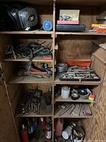 Full cabinet view showing mixed tools on shelves, including pipe wrenches, socket set, fire extinguishers