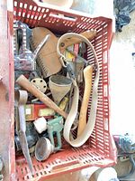 Tools in red crate including saw, staple gun, funnels, strap