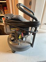 Overall view of NITA pancake air compressor showing handle, hose, motor housing, wheels