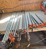 Top view of full set of pipe and bar clamps laid out on workbench