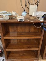 Front view of brown three-shelf bookcase with motion-sensor lights on top