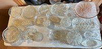 Overview of entire lot with multiple pressed and cut glass pieces on table