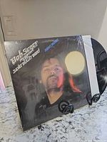 Front cover of Night Moves album on stand, shrink wrap visible, record partly exposed