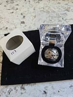 ring in clear acrylic box beside small white sleeve