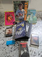Group shot of all items: Bewitched VHS, three cassette tapes, three books