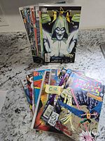 Stack and spread of approximately 18 assorted comic books displaying several cover titles