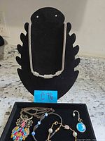 Front view showing rhinestone collar necklace on stand with other jewelry pieces in tray