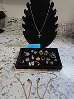 Overview showing cross necklace, tray of assorted jewelry, goldtone chain
