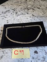 Full view of silver-tone bike chain necklace in black velvet case