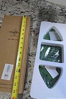 Closed Willow Tree cardboard box beside foam tray showing packed green metal panels; tape measure indicates size