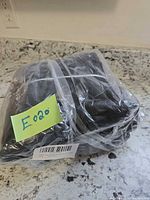 Plastic-wrapped folded black insulated pizza bag with lot note visible