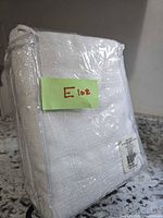 Front view of packaged white curtain panel with lot note