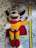 Front view of Mighty Mouse plush with tape measure showing height