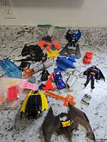 Overview of assorted Batman toys and parts spread on countertop