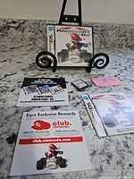 Full contents laid out: case on stand, cartridge, manual, inserts