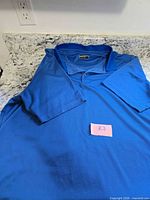 Front view of blue Bollé golf shirt laid flat