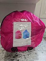 Front view of pink circular carry bag displaying product sheet