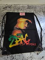 Front side color graphic showing Tupac, rope straps and grommets visible