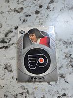 Front of Bobby Clarke Upper Deck Trilogy patch card showing player image and embroidered Flyers logo patch