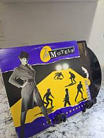 Front cover of The Motels Little Robbers LP on stand, vinyl partially visible