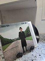 Front jacket of album on stand with partially visible vinyl and inner sleeve