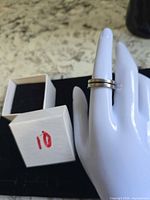 Ring displayed on hand form beside small white box numbered 10