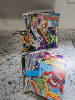 Stack and upright display of assorted comic books showing covers for The Defenders, Lords of the Ultra Realm, X and others