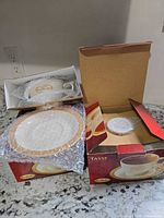 Two open Tim Hortons boxes showing bubble-wrapped cup and saucer sets