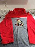 Full pullover laid flat showing red sleeves, grey body, Senators logo