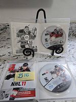 Open cases displaying NHL 14 and NHL 11 PS3 game discs and inserts