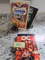 Snow White VHS with clamshell and The O.C. Season 1 DVD case