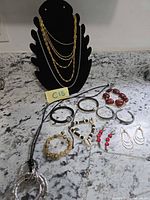 Entire lot showing necklaces on black bust and assorted bracelets and earrings on counter