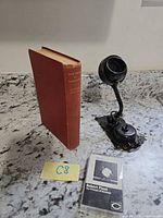 All three items grouped: candlestick phone receiver, red hardcover book, Robert Plant cassette