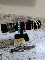 Full view of bracelets on display stand plus braided bracelet on counter
