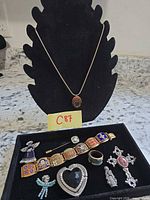Group shot showing necklace on bust and nine additional jewelry pieces in tray