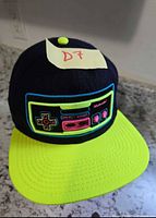 Front view showing NES controller embroidery and neon yellow brim