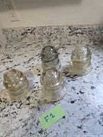 Four clear glass insulators on countertop